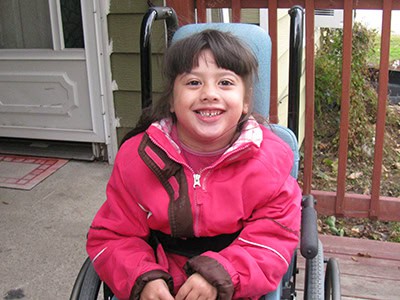 Mia sitting in wheelchair on her new ramp at her house